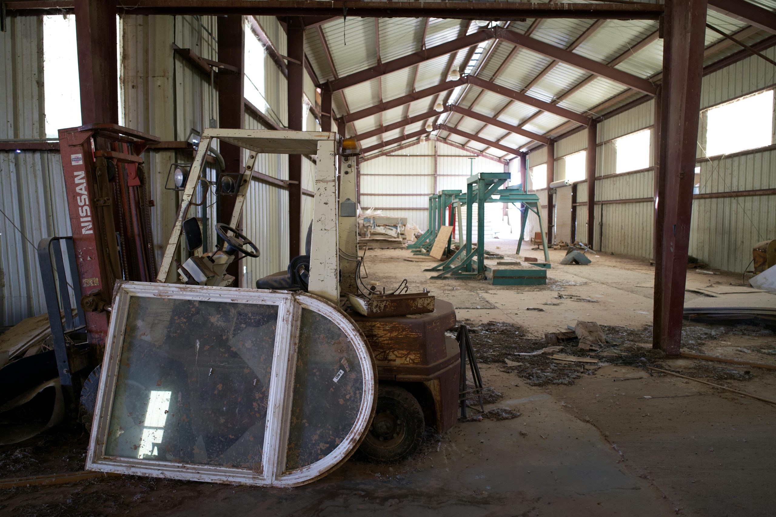 Inside view of an abandoned warehouse with old forklift and scattered debris.